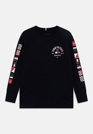 Schwarzes Langarmshirt mit weißen und roten nautischen Flaggenmotiven auf den Ärmeln und Tommy Hilfiger Logo mit Text auf der oberen Brust.