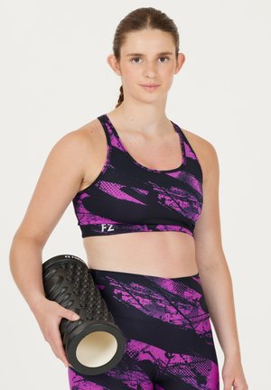 Lilla og sort sports-bh med abstrakt mønster, parret med matchende leggings. Personen holder en sort tekstureret skumrulle.