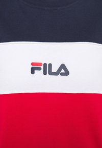 Rood, wit en marineblauw kortmouwenshirt met Fila-logo. Kenmerkt zich door horizontale kleurvakken en een soepele katoen textuur.