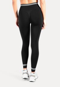 Svarta leggings med en hög midjeresår som har en kontrasterande ljus randig detalj. Mjukt, stretchigt tyg med en slät yta.