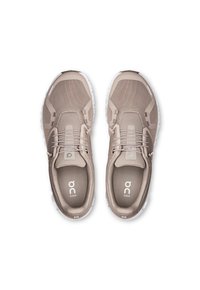 Beige athletic shoes with a mesh upper, rounded toe, elastic laces, logo detailing, and a cushioned sole. Smooth texture, modern design.