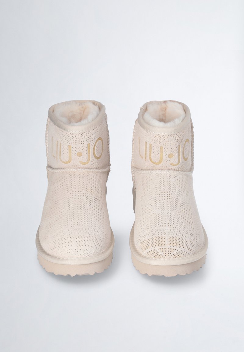 Ein Paar beige Knöchelstiefel mit perforiertem Design und Teddyfell-Futter, mit goldfarbenem "LIU•JO"-Logo auf dem vorderen Schaft.