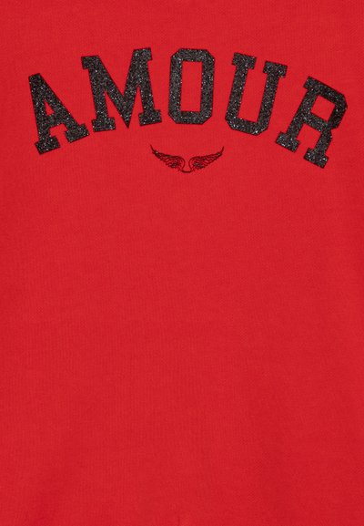Punane tõmblukk, millel on sõna "AMOUR" sädelevates mustades tähtedes ja väike tiiva graafika all. Pehme ja sile tekstuur.