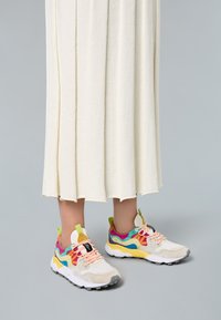 Colorful sneakers featuring a mix of white, pink, yellow, and blue accents, with textured materials and contrasting laces.