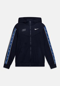 Námořnická modrá Nike mikina na zip s kapucí, předními kapsami, bílým logem Nike na hrudi a modrými pruhy s bílými swooshi na rukávech.