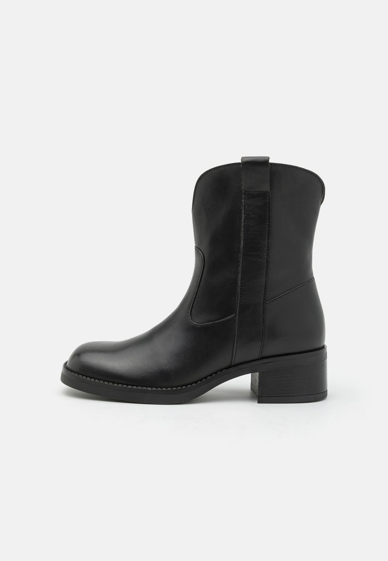 Bota negra de cuero hasta el tobillo con puntera redondeada, paneles laterales elásticos y un tacón bajo cuadrado. Textura suave con detalles de costura mínimos.