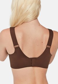 Sostén marrón con tirantes anchos y una tela suave y elástica. Ganchos ajustables en la parte posterior ofrecen soporte y flexibilidad en el ajuste.