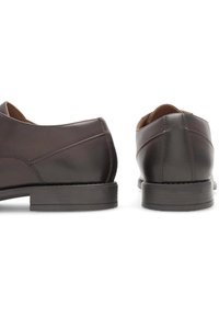 Brūni ādas apavi ar gludu tekstūru, apaļu purngalu un zemu papēdi; raksturīgas smalkas izšūtas detaļas sānos.