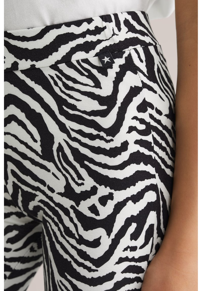 Svart- och vitrandiga leggings med zebramönster, med en slät textur och en platt midjeresår samt en liten stjärndetalj nära midjan.