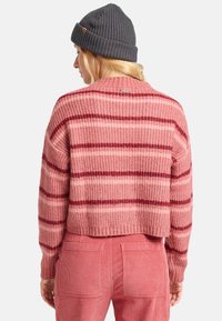 Gestrickter Pulli aus Häkelarbeit in rosa und burgunderfarbenen Streifen mit einer verkürzten Passform, geripptem Saum und Bündchen. Kombiniert mit rosafarbenen Cordhosen.