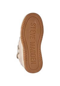 Rubberen sneakerzool in licht bruin met een textuur voor grip. "STEVE MADDEN" prominent in het midden geëtst. Zachte bovenkant met een subtiele bontaccent.