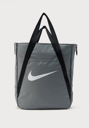 Šedá taška přes rameno Nike s černými rukojeťmi a bílým logem swoosh na přední straně, zobrazena na jednoduchém bílém pozadí.