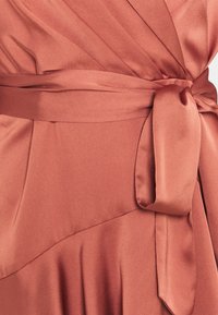 Abito in satin di un caldo colore terracotta, con morbide pieghe e una cintura legata in vita per una vestibilità sicura. Texture liscia con design drappeggiato.