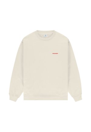 Bēšs džemperis ar apaļu kakla izgriezumu, garām piedurknēm un nelielu sarkanu "POCKIES" logotipu kreisajā krūtīs.