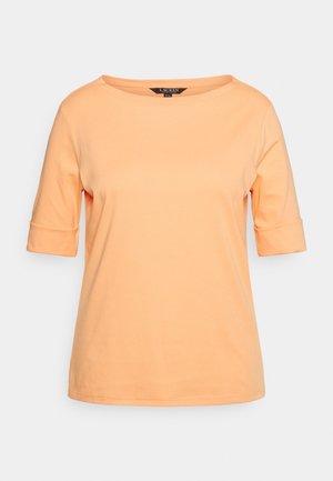 Haut femme à manches courtes de couleur pêche avec encolure ronde et poignets repliés sur fond uni.