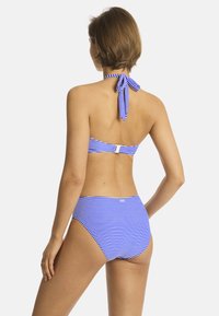 Bikini a righe blu e bianche con scollo all'americana e laccetto sul retro, dotato di una chiusura sulla fascia e slip a vita alta. Tessuto morbido.