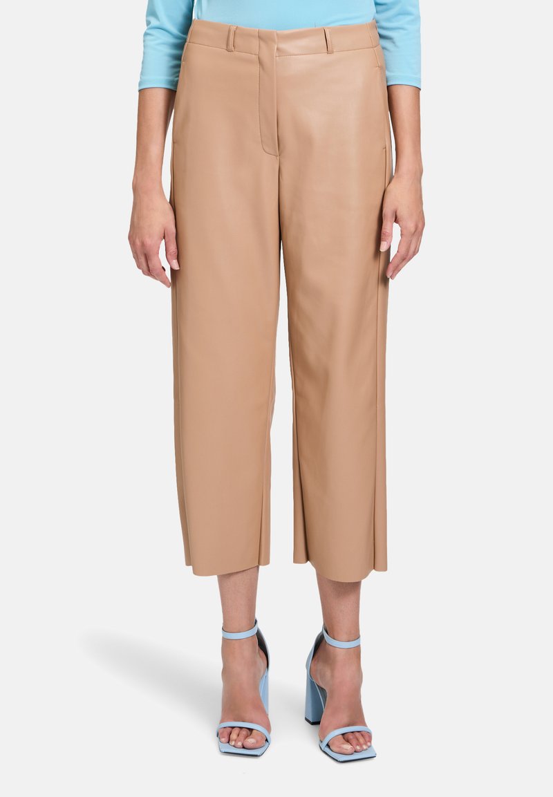 Beige leren cropped broek met een wijduitlopend ontwerp, zijzakken en een zachte textuur, gedragen met lichtblauwe sandalen met blokhak en bandjes.