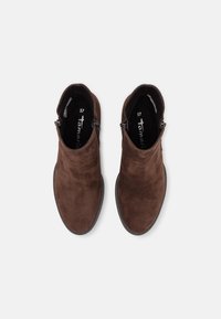 Une paire de bottines en daim marron avec des fermetures éclair sur le côté et des bouts ronds, vues de dessus sur un fond blanc uni.