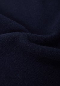Tessuto di un blu navy scuro, con una superficie morbida e pelosa e delicate pieghe che creano aree d'ombra.