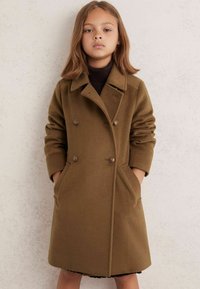 Rudas dvigubas vilnos paltas su įpjautu apykakle ir dviem priekinėmis kišenėmis. Yra dekoratyviniai mygtukai ir pritaikytas siluetas.