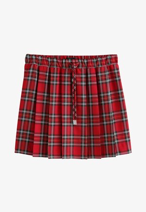 Punane ja must ruuduline pliseeritud seelik elastse vöökoha ning esiotsa nööriga valge tausta ees.