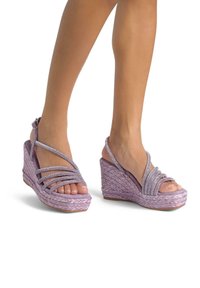 Sandali a cuneo viola con texture intrecciata e cinturini decorativi. Presentano punta aperta e cinturini alla caviglia per supporto.