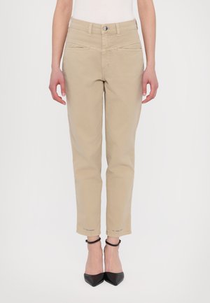 Beige cropped trousers with a smooth texture, featuring pockets, a button closure, and contrasting stitching details. Worn with black heels.