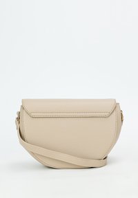 Béžová kožená crossbody taška s zakriveným tvarom, uzatváraním na klopu a jednoduchým popruhom. Textúrovaný povrch a minimálne kovové detaily.