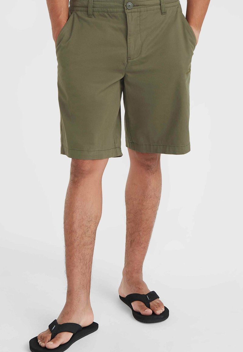 Olivgrüne Shorts aus leichtem Stoff, ausgestattet mit zwei Seitentaschen, Frontknopfverschluss und einer lässigen Passform. Getragen mit schwarzen Flip-Flops.