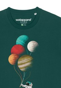 T-shirt vert foncé représentant un astronaute tenant cinq ballons dessinés comme des planètes, avec des couleurs et textures variées.