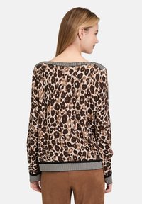 Sweter w panterkę z miękkiego materiału, cechujący się długimi rękawami, szerokim dekoltem oraz paskiem w czarno-białe paski. Dominuje brązowa tonacja w wzorze.