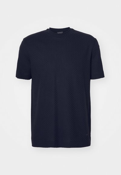 Σκούρο μπλε κοντομάνικο μπλουζάκι φτιαγμένο από υφασμάτινη επιφάνεια με στρογγυλή λαιμόκοψη και διακριτές λεπτομέρειες σχεδίου, με μικρή λογότυπη πινελιά.