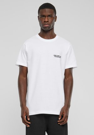 White cotton t-shirt with a crew neckline, featuring a small black printed text detail on the left chest, paired with black shorts.
