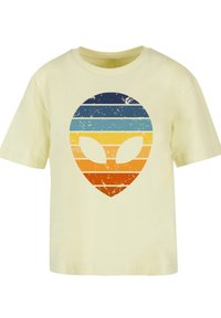 Light yellow cotton t-shirt featuring a distressed graphic of an alien face with horizontal stripes in blue, teal, orange, and yellow.