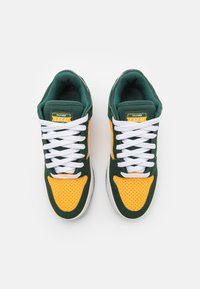 Pair of green and yellow sneakers with white laces, viewed from above on a white background.