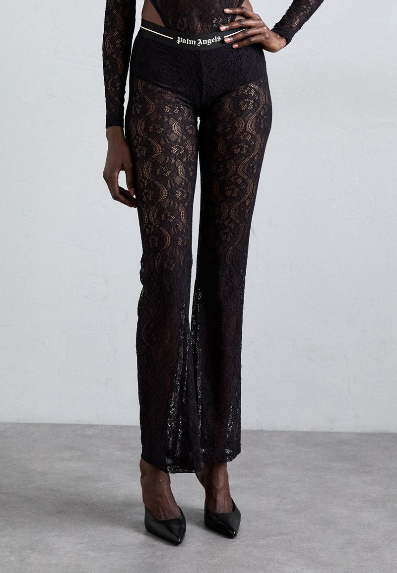 Black lace pants with a fitted waistband featuring the "Palm Angels" logo. The fabric has a floral pattern and flows to a wide leg design.
