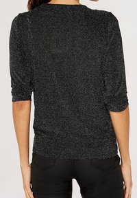 Pull noir avec des éclats argentés, manches trois-quarts, et encolure arrondie. Coupe ajustée avec texture côtelée à l'ourlet.