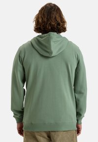 Hoodie en coton vert avec capuche à cordon, poignets côtelés et ourlet. Texture lisse avec une coupe décontractée. Aucune graphique ou motif visible.