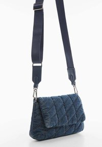 Torebka typu crossbody z pikowanego denimu, z klapą, w ciemnoniebieskim kolorze, z regulowanym materiałowym paskiem i srebrnymi akcentami. Teksturowana powierzchnia.