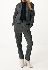 Veste à motif pied-de-poule gris avec une fermeture éclair et pantalon taille élastique, assortis à des bottines crème à talon bloc. Tissu texturé.