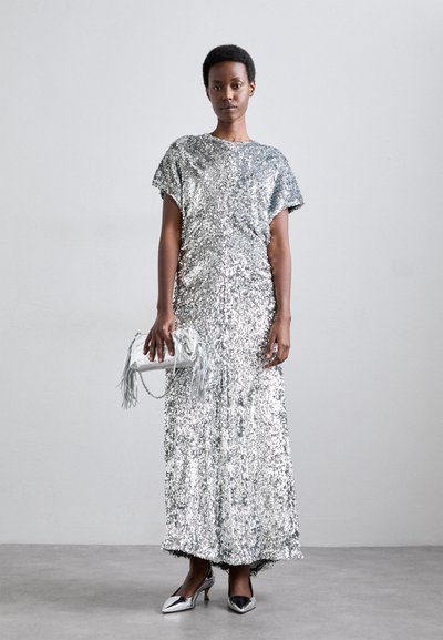 Silver sequin dress with short sleeves, floor-length design, paired with a fringed silver clutch and metallic high-heeled shoes.