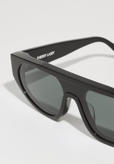 Mustad mustprisud, nurgeliku kujuga raam, tumedat tooni läätsed ja "Thierry Lasry" logo trükitud käele. Loodud stiilse, läikiva viimistlusega ja kindla kujundusega.