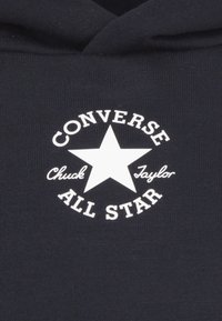 Zwarte sweatshirt met een wit rond logo met een ster, met de tekst "CONVERSE Chuck Taylor ALL STAR" op de borst.