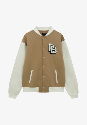 Beige og hvid varsityjakke med trykknapper, to forlommer, ribbet krave og manchetter, med et sort og hvidt "PB" logo på brystet.