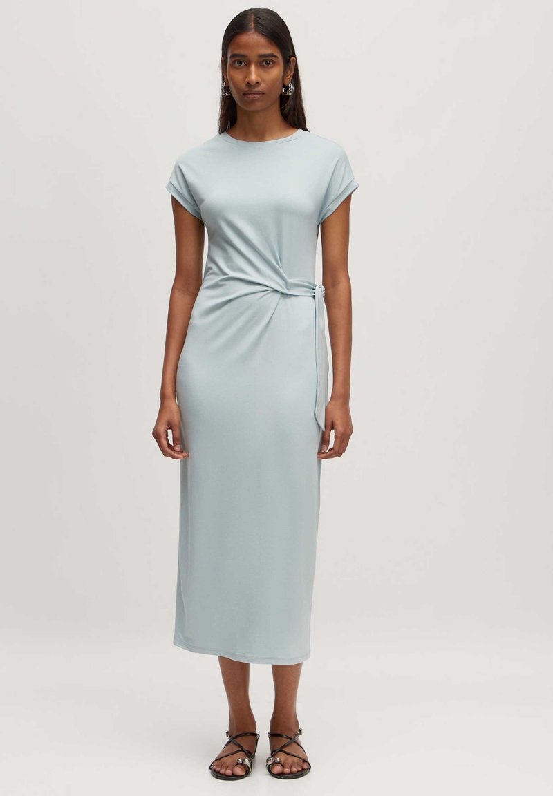 Lichtblauwe midi-jurk gemaakt van zachte stof, met een gedraaide detail ter hoogte van de taille, korte mouwen en een rechte silhouet.