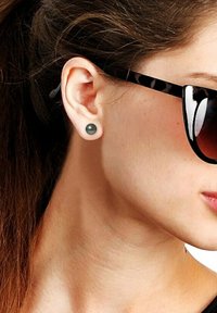 Pure spinelle grise en piercing cartilage, finition lisse. Modèle portant des lunettes de soleil noires, mettant en valeur un design épuré et minimaliste.