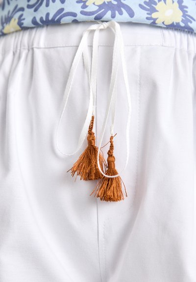 White pants with an elastic waistband, featuring two white drawstrings ending in brown tassels. The design includes a smooth texture.