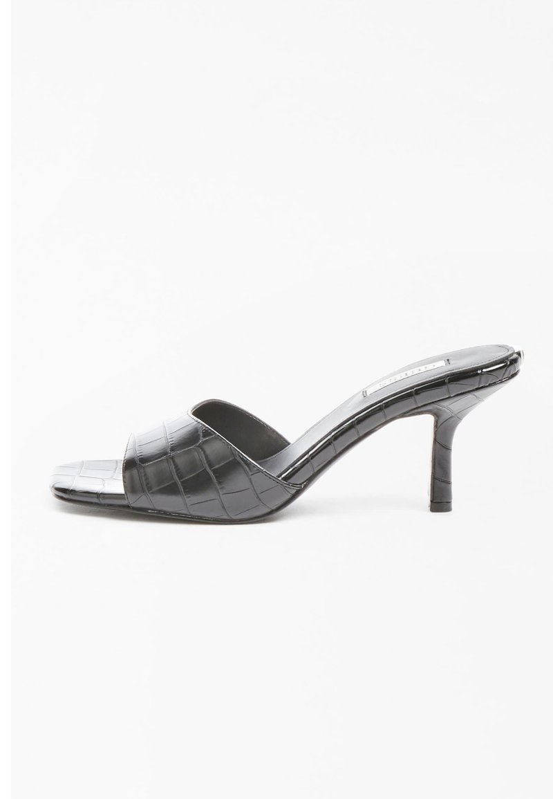 Mules noires à talons avec un motif crocodile. Design à bout ouvert, finition lisse et un talon fin de 3 pouces. Silhouette élégante et minimaliste.