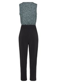 Zwarte jumpsuit met een mouwloze top van een teal stof versierd met zwarte stippen, een elastische tailleband en een taps toelopend broekontwerp.