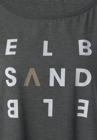 Dunkelgraues T-Shirt mit rundem Halsausschnitt, das auffällige, gemischte Typografie in weißen und braunen Buchstaben zeigt, einige davon sind in der Ausrichtung umgekehrt.